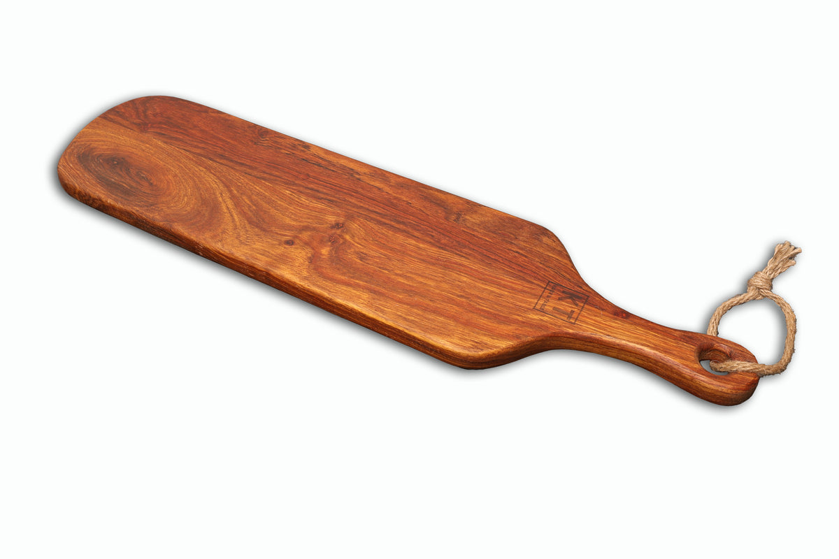 Medium handcrafted wooden paddle serving board with rope handle, shown at an angle